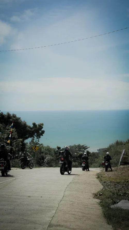 Motorizados en una carretera de montaña frente al mar