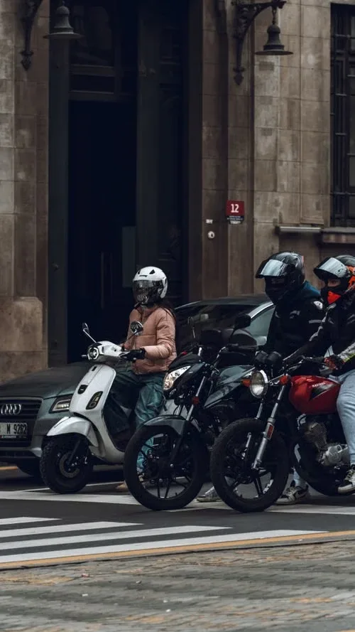 Motorizados con casco esperando en un cruce